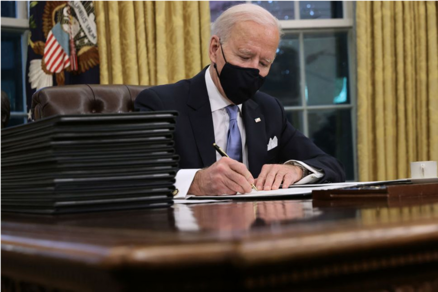 Biden signing executive orders at the Whitehouse.