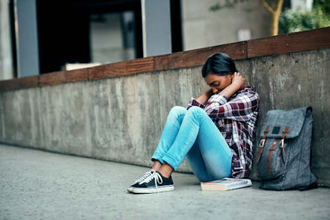A picture displaying a teenage girl riddled with anxiety and unease while in school.
