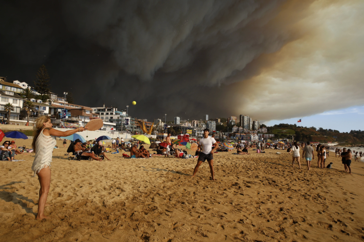 Visitors at Viña del Mar pictured playing paddle board near rising smoke from the wildfires. 