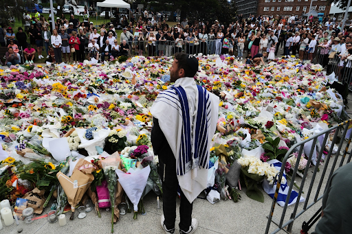 Rabbi Yossi Friedman speaks to people gathering at a flower memorial by the Bondi Pavilion at Bondi Beach on Tuesday, Dec. 16, 2025 (POLITICO) 